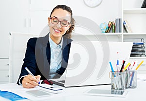 Business lady sitting at office desk with laptop