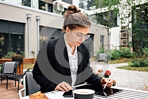 Business lady sitting on veranda in coffee shop while working by digital social media project on tablet computer. Young creative f