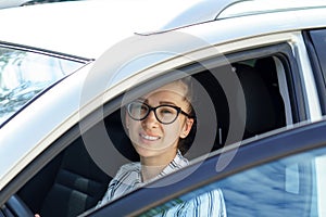 Business lady tears off the car holding a phone in his hand. Young attractive girl in a business style in a shirt and black pants