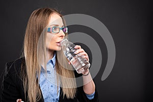 Business lady wearing blue glasses drinking from bottle of water