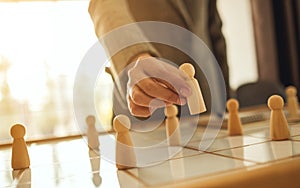 Business leader choosing wooden people from a group of employees on a planning board