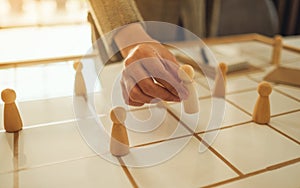 Business leader choosing wooden people from a group of employees on a planning board