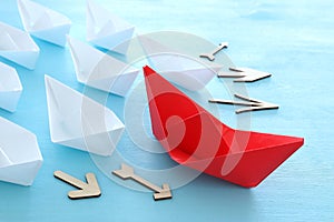 Business. Leadership concept image with paper boats on blue wooden background. One leader guiding others