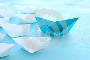 Business. Leadership concept image with paper boats on blue wooden background. One leader guiding others