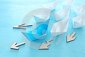 Business. Leadership concept image with paper boats on blue wooden background. One leader guiding others