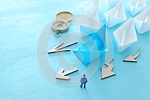 Business. Leadership concept image with paper boats on blue wooden background. One leader guiding others