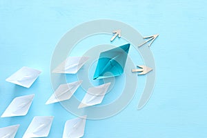 Business. Leadership concept image with paper boats on blue wooden background. One leader guiding others