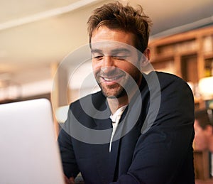 Business at leisure. a handsome young man sitting with a laptop in a cafe.