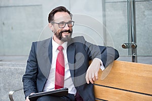 Business, Leisure, technology, communication and people concept-man with tablet on city street bench. Portrait of handsome man