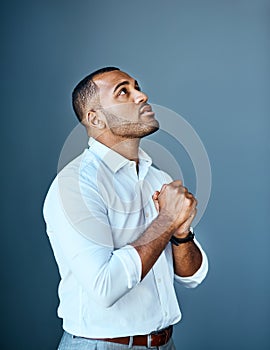 When business looks down, start looking up. Studio shot of a young businessman looking up with his hands clasped in