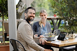 Business lunch for two managers, discussing new business project. Couple sitting outdoors on terrace restaurant, having