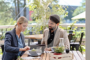 Business lunch for two managers, discussing new business project. Couple sitting outdoors on terrace restaurant, having