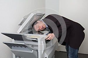 Business male in trouble with the copy machine at work