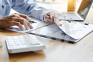 Business man accountant calculate business report and marketing data, financial graph while working on laptop computer with
