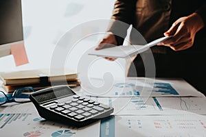 Business man analysis financial report on working desk and couting with calculator