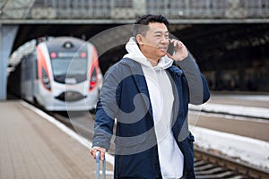 Business man Asian man at the train station having fun talking on the phone, a passenger arrived on a business visit to a new city