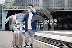Business man Asian man at the train station having fun talking on the phone, a passenger arrived on a business visit to a new city