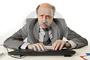 Business man with bald head on his 60s working stressed and frustrated at office computer laptop desk looking tired