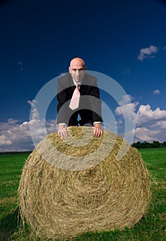 Business man on a bale of hay