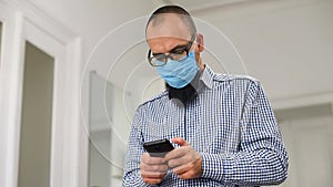 Business man with beard and in medical mask. Businessman using smart phone. Man in medical mask texting message on mobile phone.