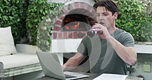 Business man, beer and laptop for remote work from home in garden, reading or typing with documents. Entrepreneur