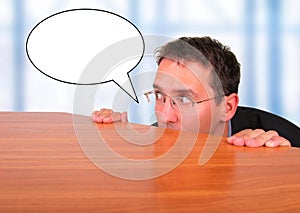 Business man behind desk in office with speech bubble