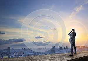 Business man and binocular spying on top of building wiht urban