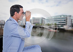 Business man with bionoculars against water across from blurry buildings photo