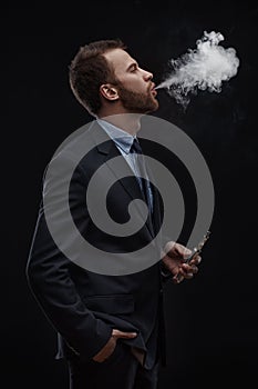 Business man blowing smoke of electronic cigarette