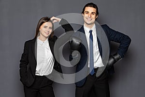 Business man with boxing gloves with a young business woman isolated on gray background