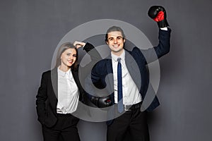 Business man with boxing gloves with a young business woman isolated on gray background