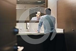 Business Man Brushing Teeth After Lunch Break In Office Bathroom