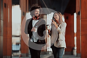 Business man and business woman talking and holding luggage traveling on a business trip, carrying fresh coffee in their