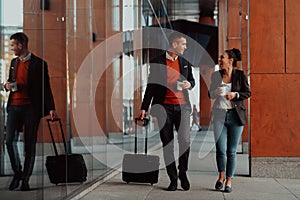 Business man and business woman talking and holding luggage traveling on a business trip, carrying fresh coffee in their