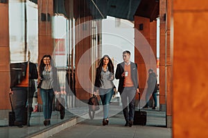 Business man and business woman talking and holding luggage traveling on a business trip, carrying fresh coffee in their