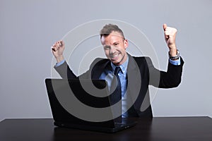 Business man cheers at laptop