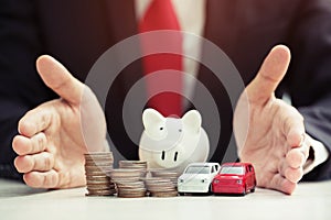 Business man and close up hand holding model of toy car red on over a lot money of stacked coins