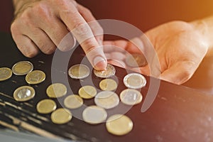 Business man counting money. rich male hands holds and count coins of different euros on table in front of a laptop. flare.