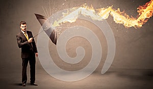 Business man defending himself from a fire arrow with an umbrella