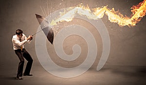 Business man defending himself from a fire arrow with an umbrella