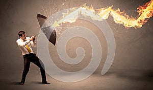 Business man defending himself from a fire arrow with an umbrella