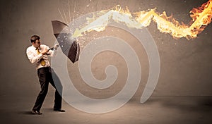 Business man defending himself from a fire arrow with an umbrella