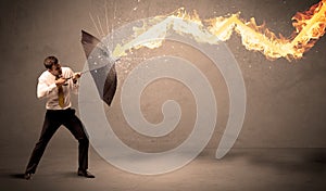 Business man defending himself from a fire arrow with an umbrella