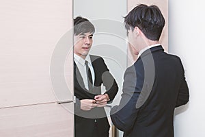 Business man dressing up for work in front of the mirror