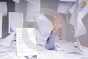 Business man drowning in a desk full of papers