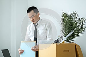 Business man employee packing document and picking up personal belongings into brown cardboard box