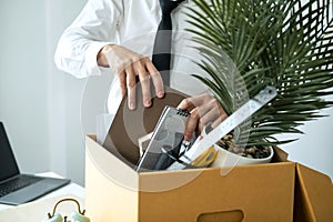 Business man employee packing notebook and picking up personal belongings into brown cardboard box