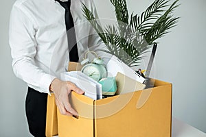 Business man employee stressful resignation from job while picking up personal belongings into brown cardboard
