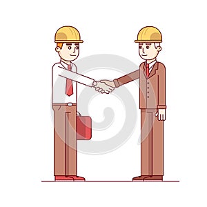 Business man and engineer standing shaking hands