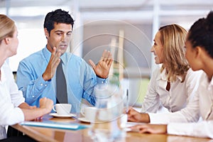 Business man expressing his views in meeting. Portrait of young business man expressing his views to female executives
